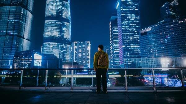 A man standing in front of tall buildings at night